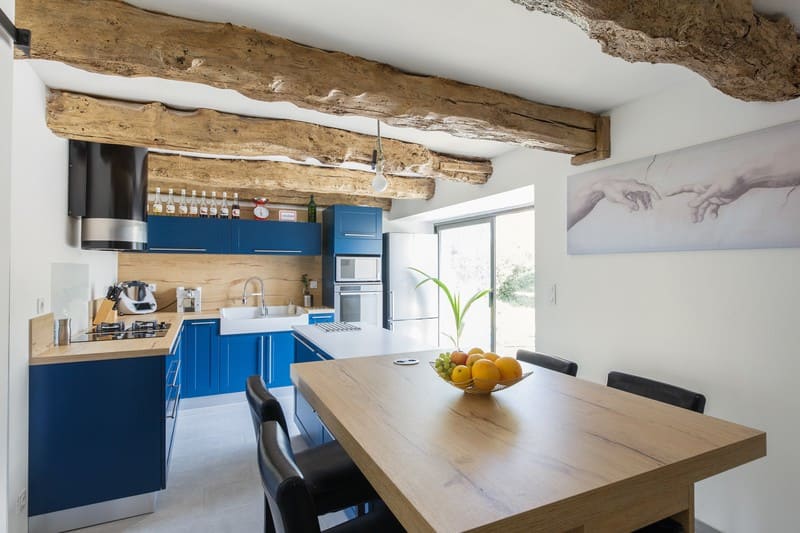 Cuisine en L blanche bois et bleue avec îlot central avec cave à Caulnes | Raison Home - 2