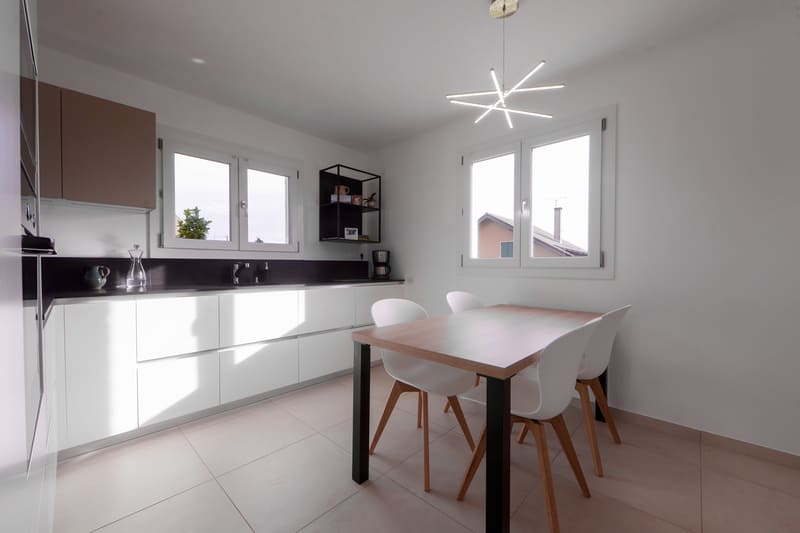 Cuisine en L avec façades blanches et plan de travail noir à Vétraz-Monthoux | Raison Home - 1