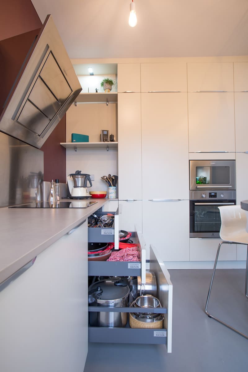 Cuisine blanche avec table en triangle avec un mur bordeau à Tours | Raison Home - 8