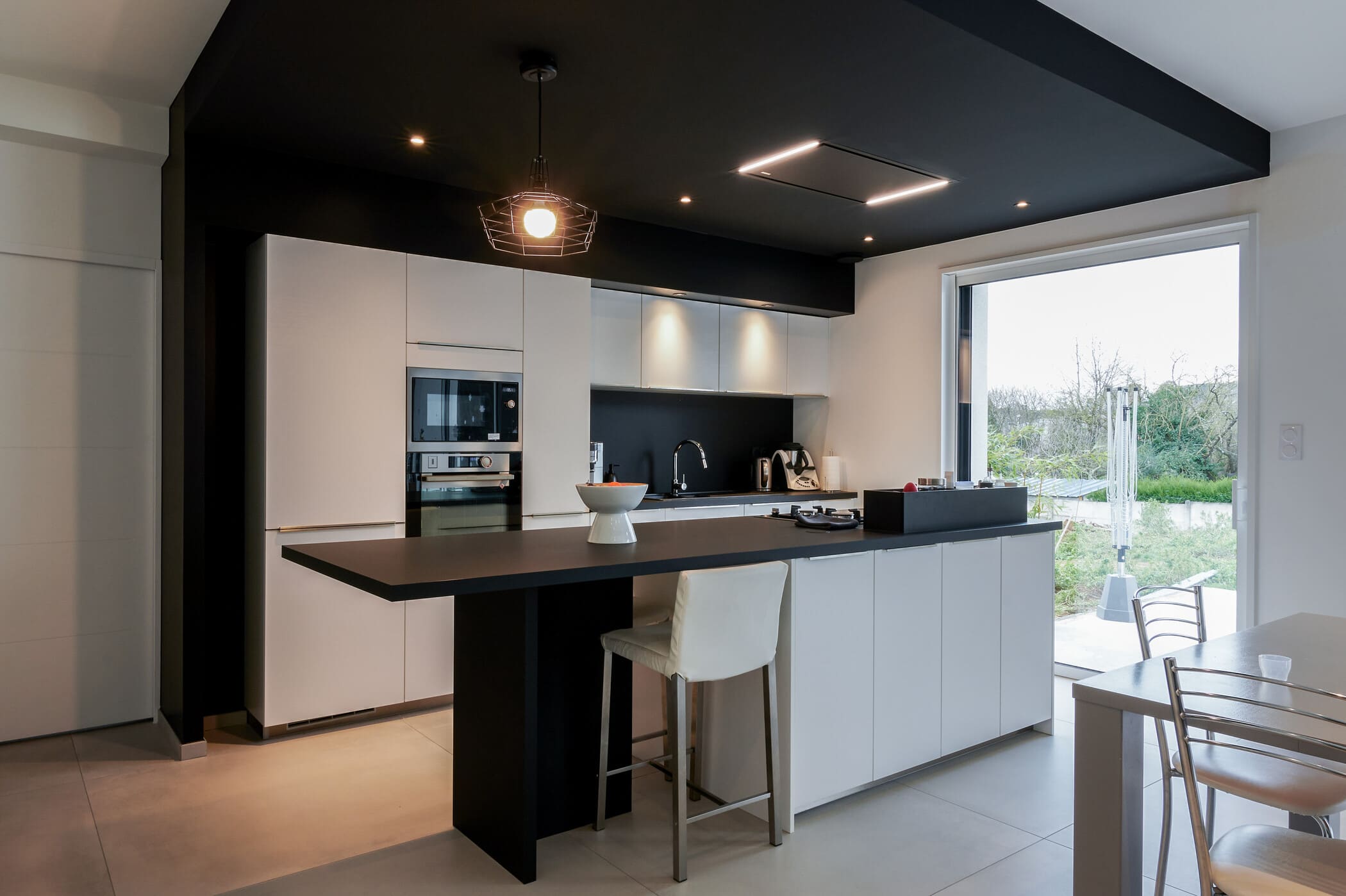 Cuisine ouverte design noire et blanche avec îlot central à Vitré | Raison Home - 1