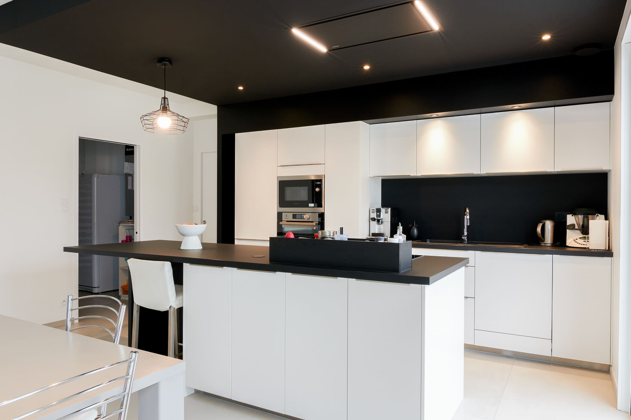 Cuisine ouverte design noire et blanche avec îlot central à Vitré | Raison Home - 3