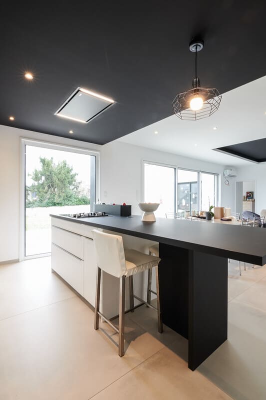 Cuisine ouverte design noire et blanche avec îlot central à Vitré | Raison Home - 4