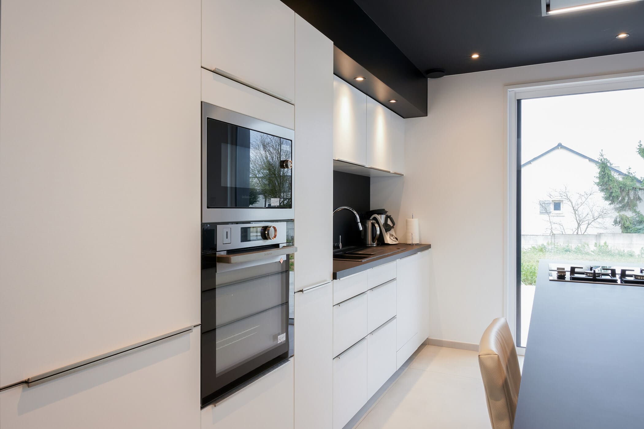 Cuisine ouverte design noire et blanche avec îlot central à Vitré | Raison Home - 6