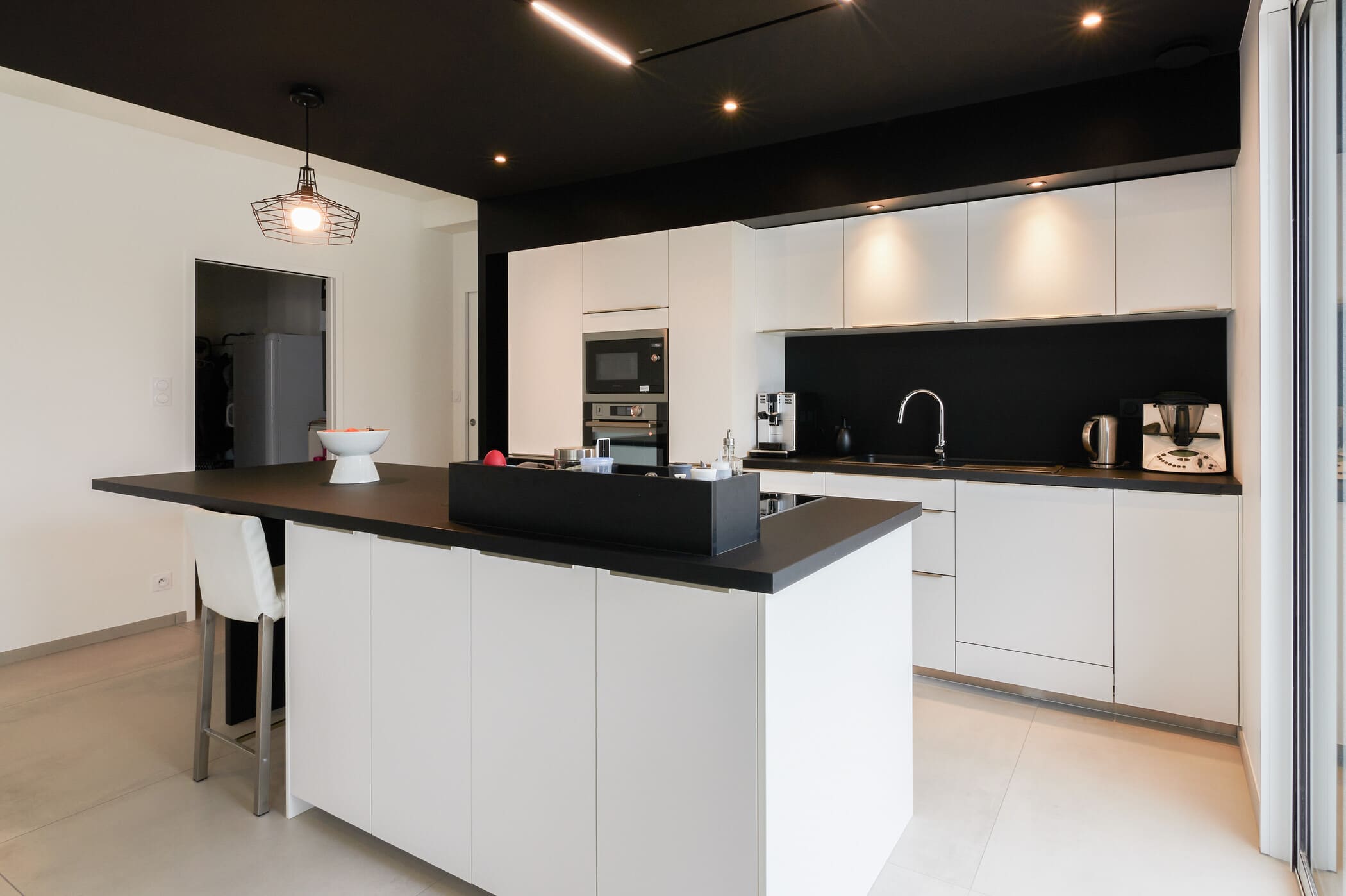 Cuisine ouverte design noire et blanche avec îlot central à Vitré | Raison Home - 8