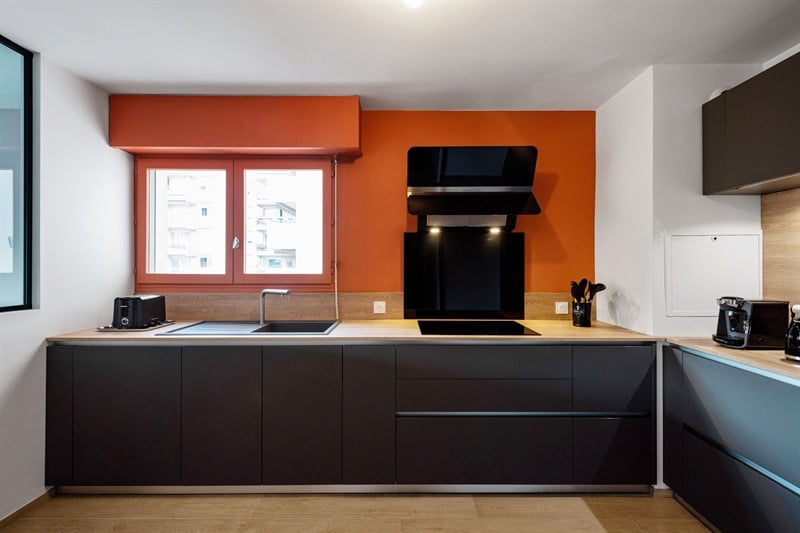 Cuisine moderne gris foncé et bois avec mur orange à Lyon 1