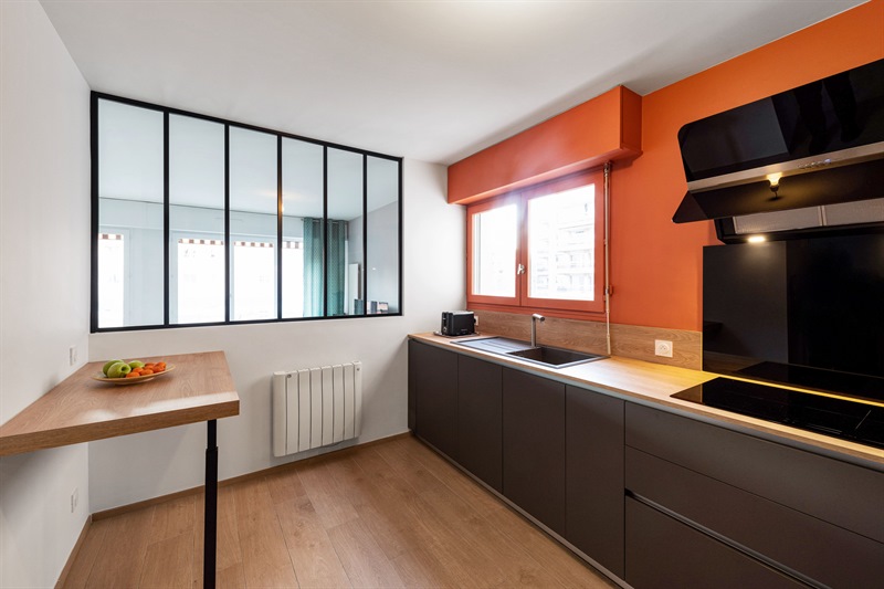 Cuisine moderne gris foncé et bois avec mur orange à Lyon 4