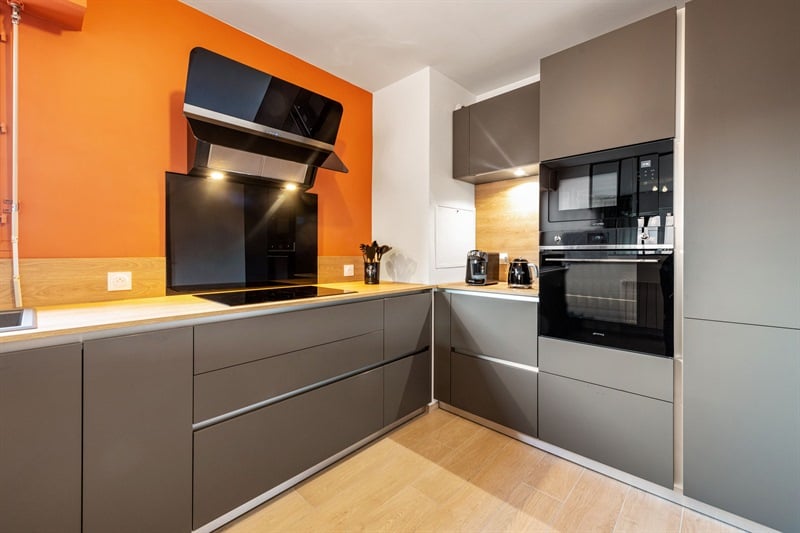 Cuisine moderne gris foncé et bois avec mur orange à Lyon 5