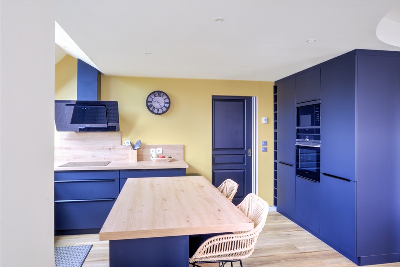 Cuisine ouverte bleu et bois avec mur jaune à Cuverville | Raison Home - 5