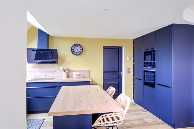 Cuisine ouverte bleu et bois avec mur jaune à Cuverville 5