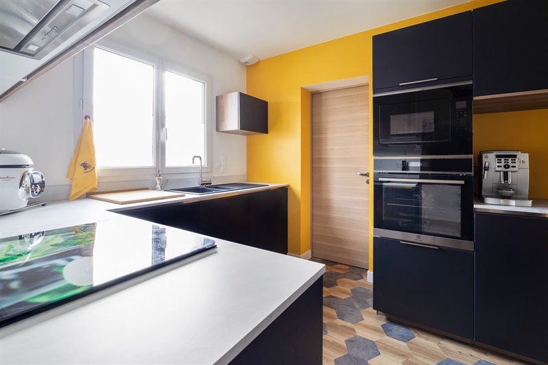 Cuisine noir, bois et blanc avec mur jaune à Plabennec | Raison Home - 1